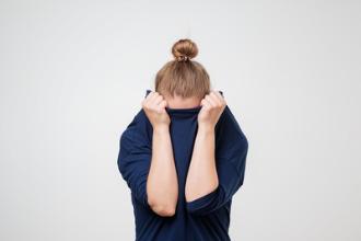 
		A woman hides her face behind her hands
	